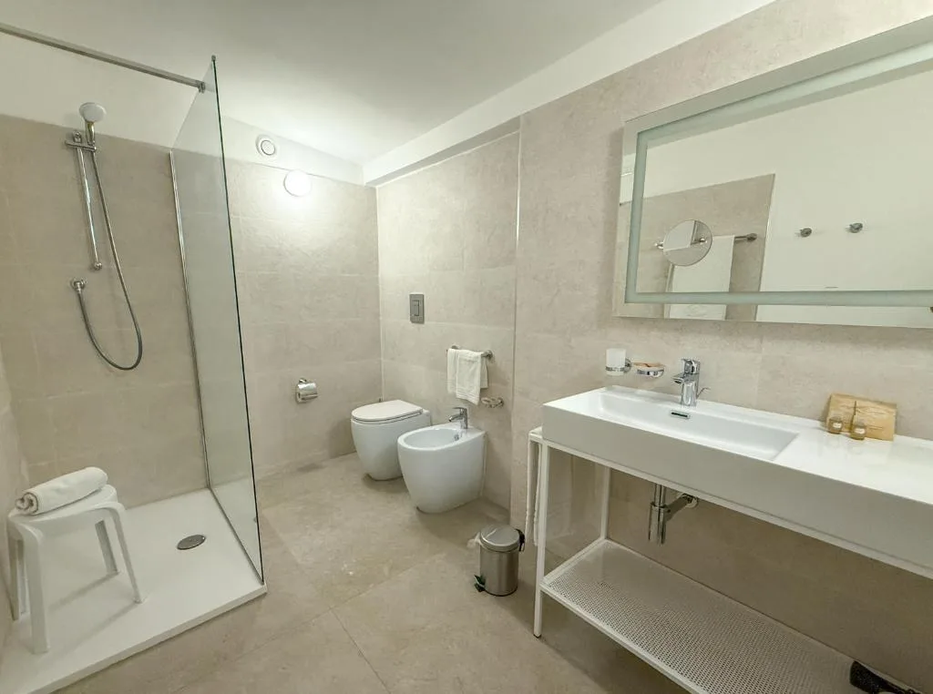 Bagno moderno con doccia in vetro, lavabo, bidet e grande specchio