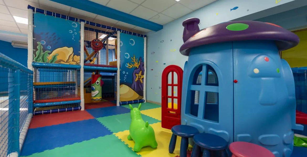 Area giochi coperta per bambini con struttura morbida e casetta colorata