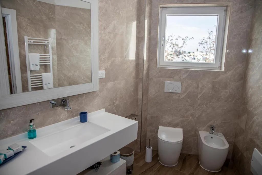 Bagno moderno con lavabo bianco, sanitari, bidet e finestra panoramica