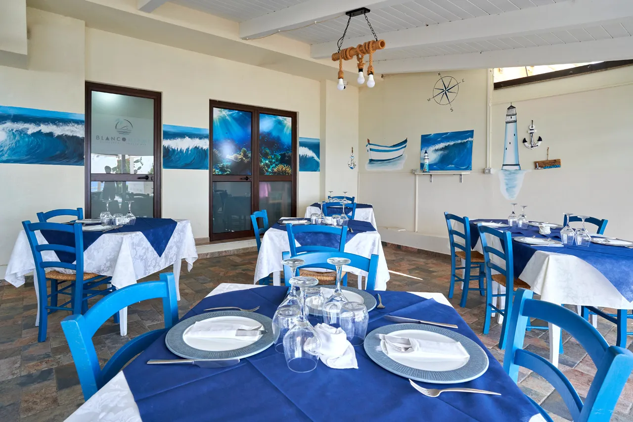 Sala ristorante con tavoli apparecchiati e sedie blu in stile marinaro