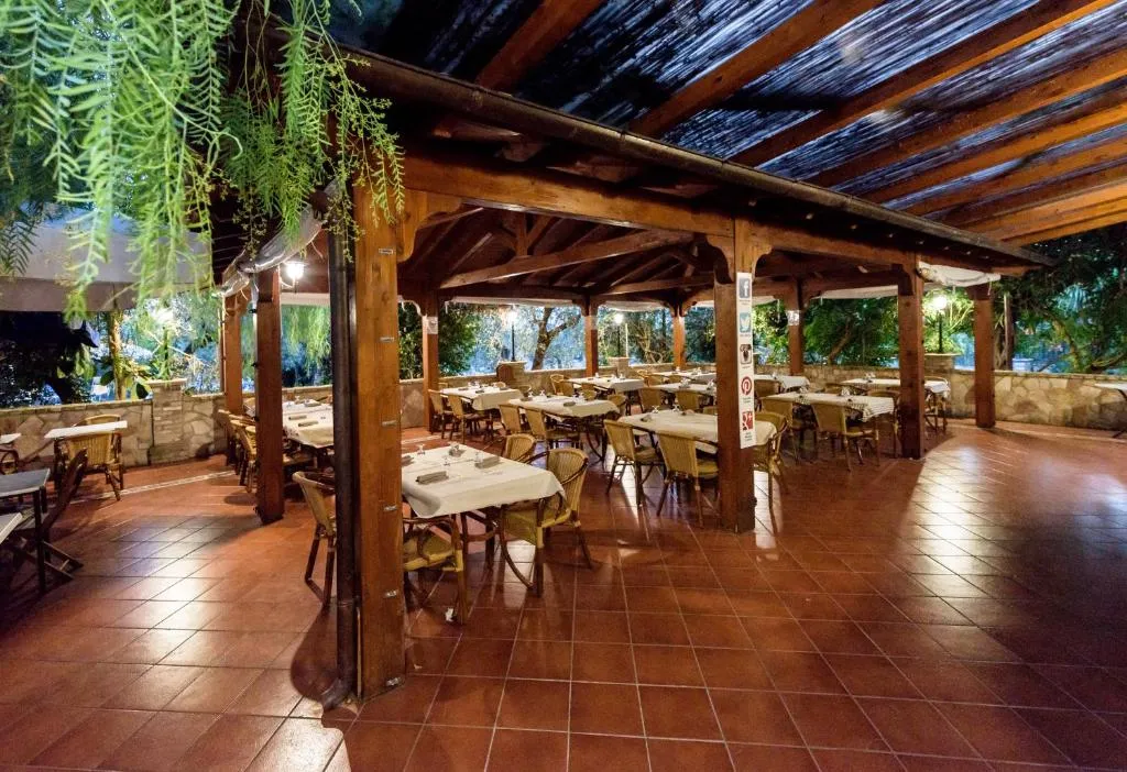 Sala ristorante coperta da pergolato in legno con tavoli apparecchiati