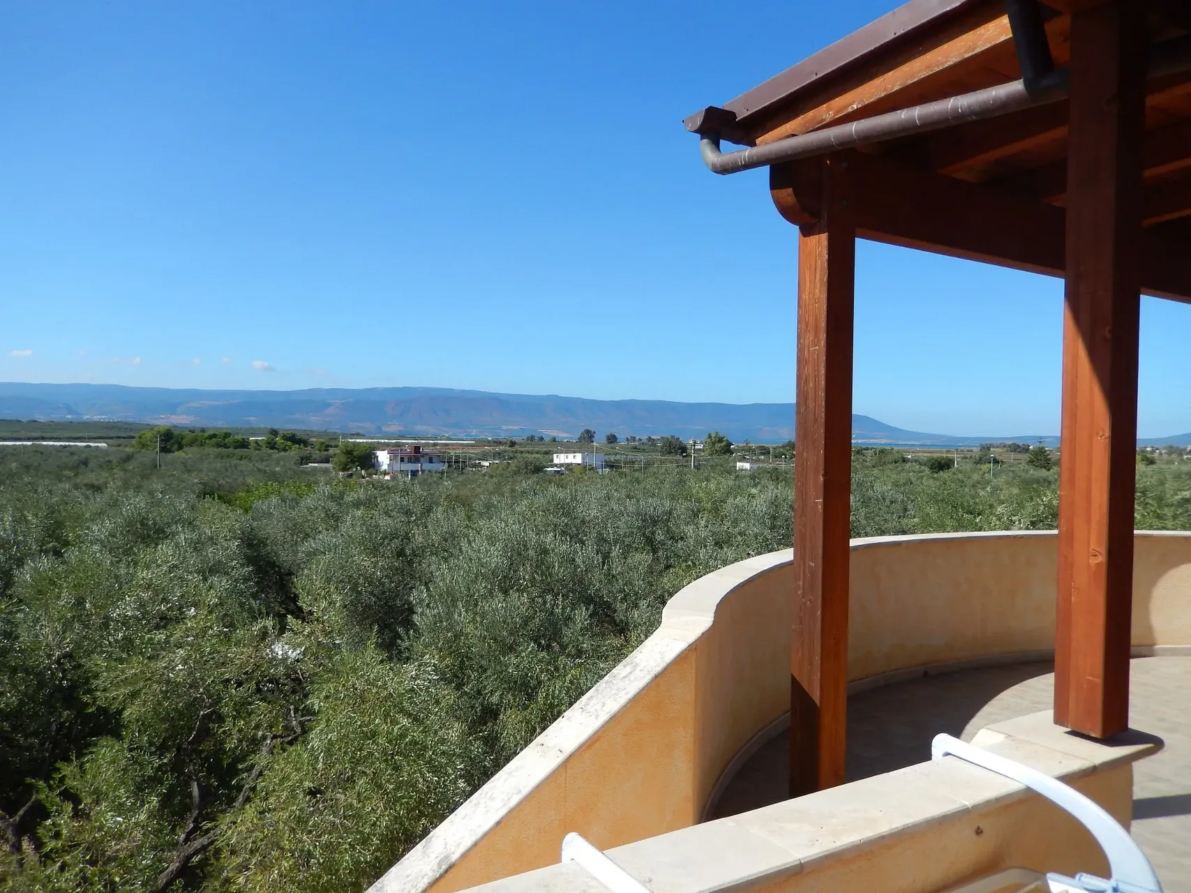 Terrazza con pergolato in legno affacciata su uliveti e colline