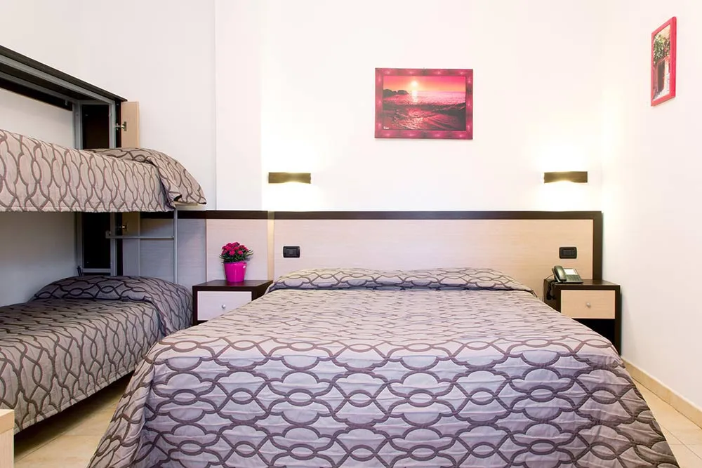 Camera con letto matrimoniale e letto a castello arredata in stile semplice