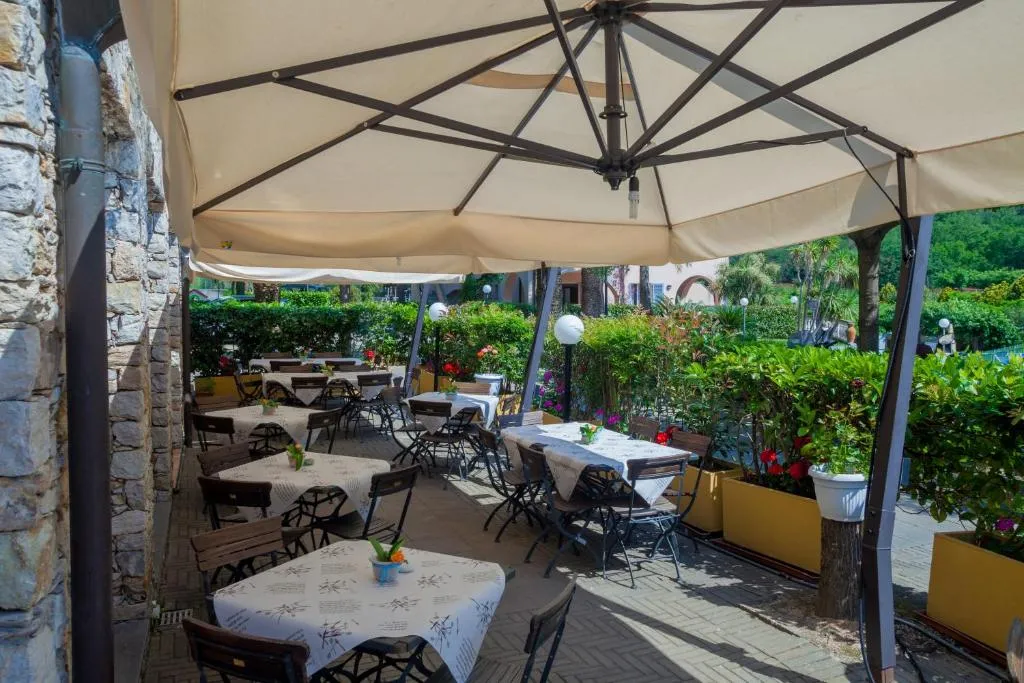 Terrazza esterna del ristorante con tavoli apparecchiati sotto ombrelloni e piante fiorite