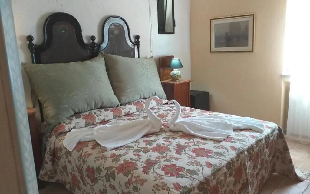 Camera con letto matrimoniale, copriletto floreale e testiera in legno decorata