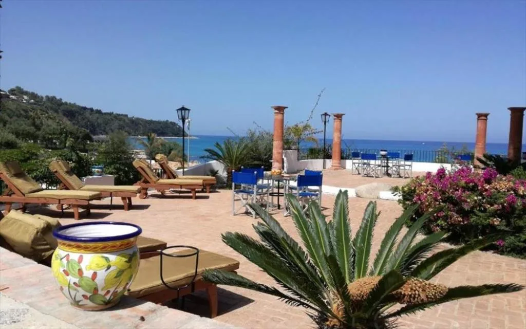 Terrazza con lettini e sedie vista mare, colonne in cotto e piante mediterranee