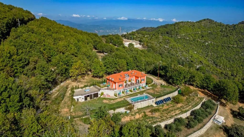 Veduta aerea della villa arancione immersa nel verde delle colline con piscina