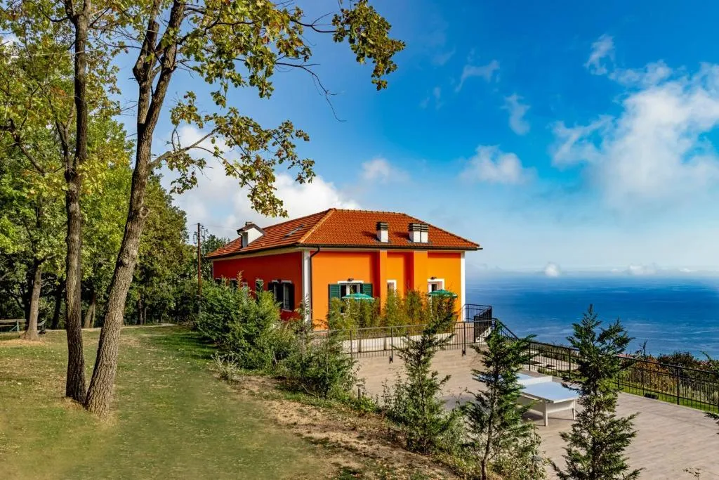 Villa arancione con tetto rosso immersa nel verde con vista sul mare