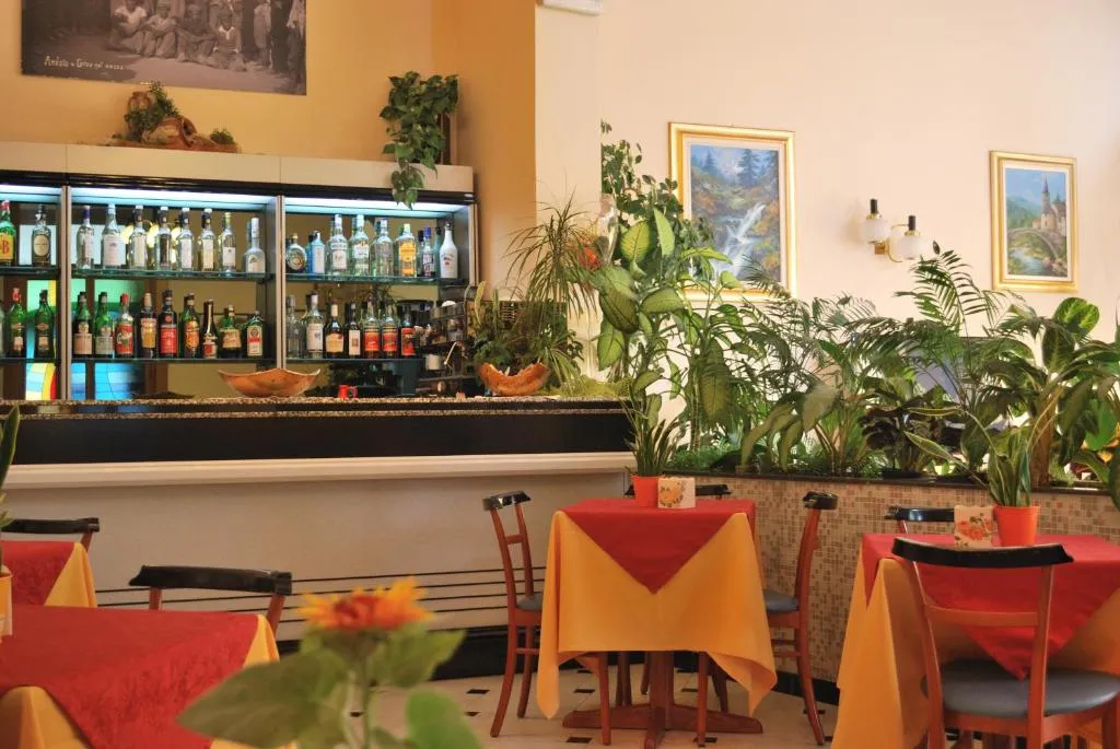 Bar dell'hotel con bottiglie di liquori, piante verdi e tavoli colorati