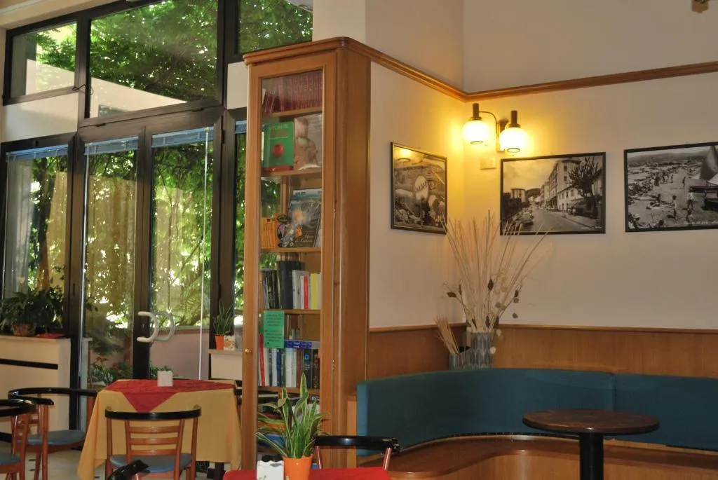 Sala interna con libreria, foto d'epoca alle pareti e divanetti