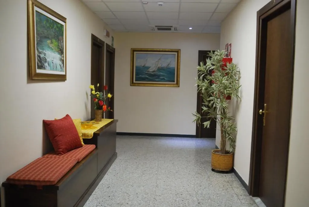 Corridoio dell'hotel con panca, quadri marini e pianta decorativa