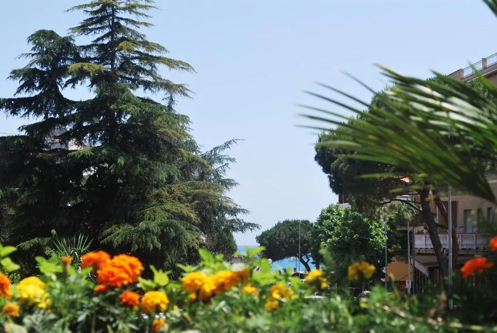 Giardino con fiori arancioni, alberi e scorcio sul mare in lontananza