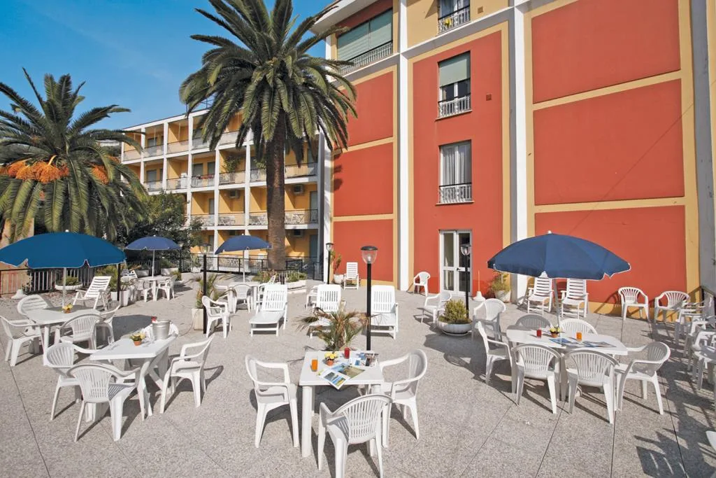 Terrazza esterna con tavoli, sedie bianche, ombrelloni blu e palme