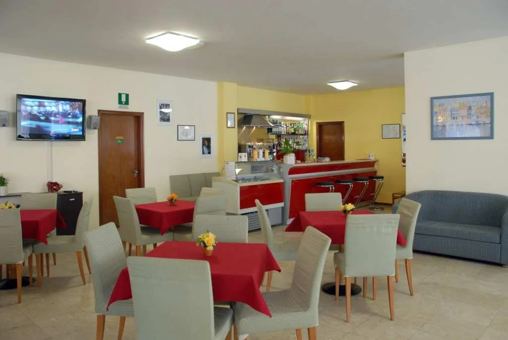 Sala bar e colazione con tavoli rossi e bancone rosso
