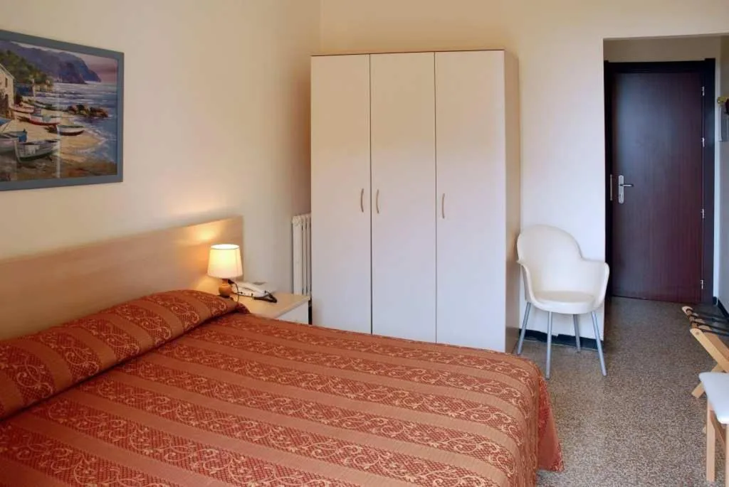 Camera semplice con letto matrimoniale, armadio bianco e sedia