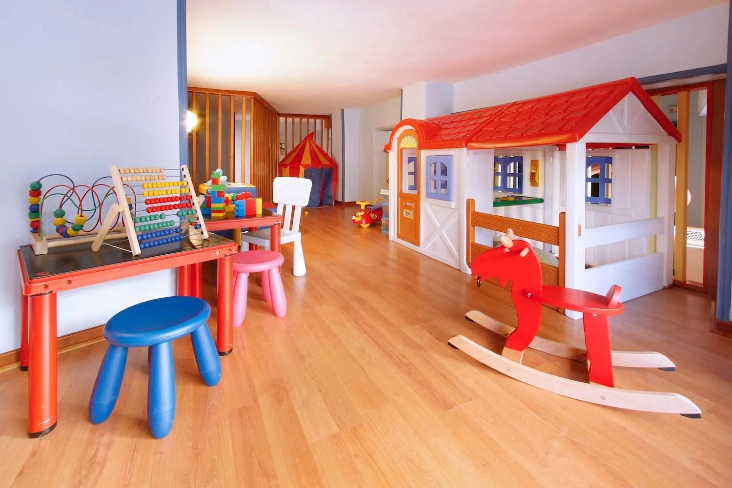 Sala giochi per bambini con casetta, cavalluccio a dondolo e giochi colorati
