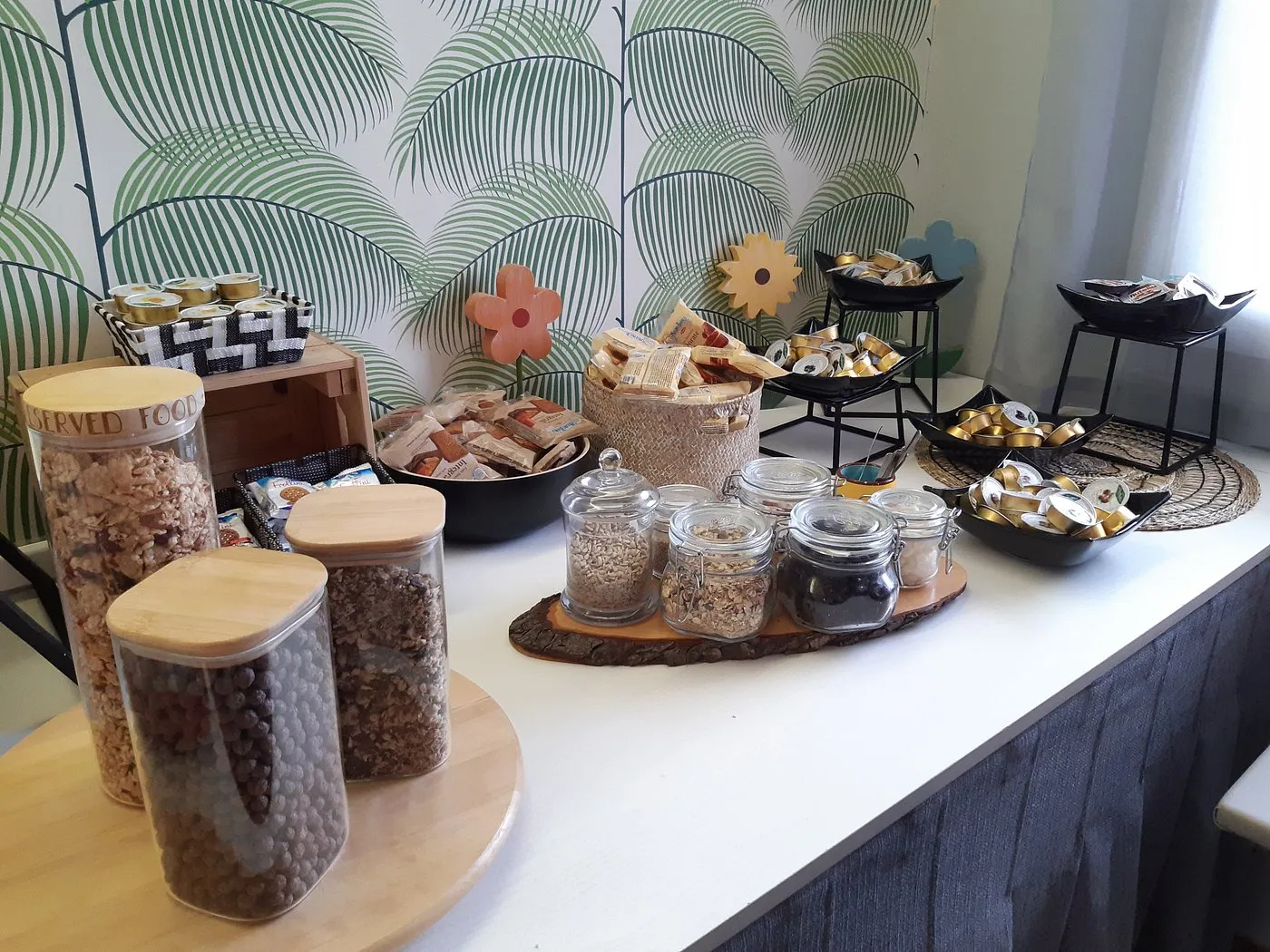 Buffet della colazione con cereali in barattoli di vetro, capsule di caffè e snack confezionati
