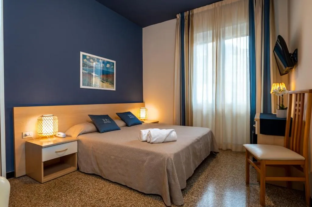 Camera elegante con parete blu, letto matrimoniale e scrivania
