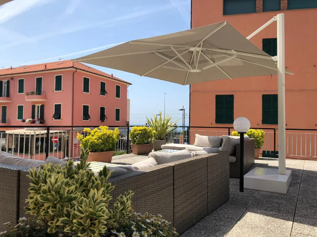 Terrazza esterna con divani in rattan, ombrellone bianco e piante