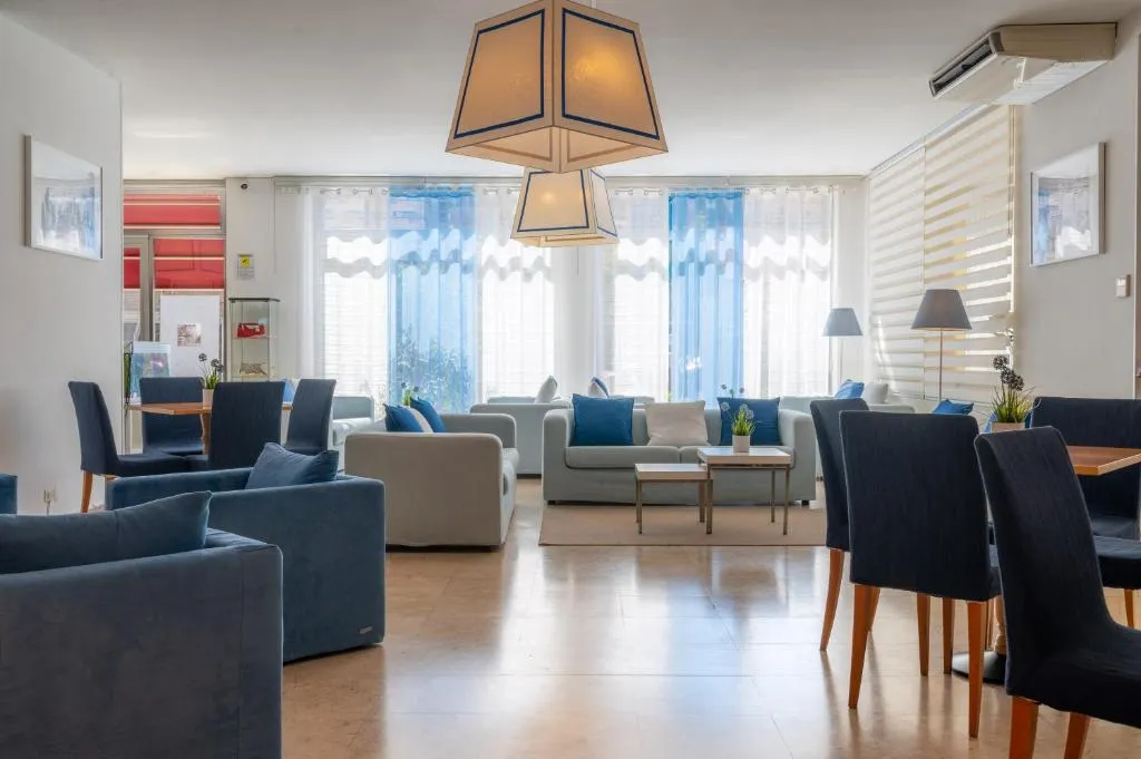 Sala comune con divani, poltrone e tavoli illuminata da grandi finestre