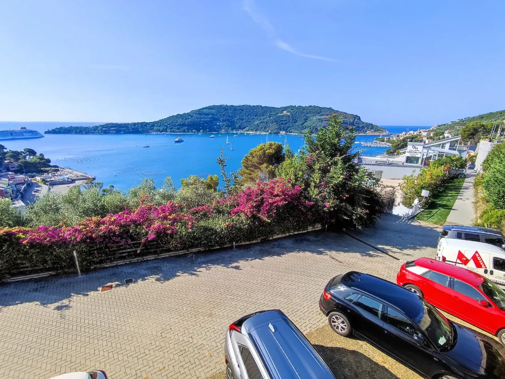 Vista sul golfo con nave da crociera, parcheggio e bougainville in fiore