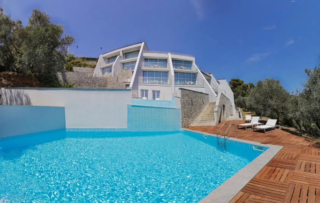 Piscina esterna con terrazza in legno e vista sull'edificio moderno dell'hotel