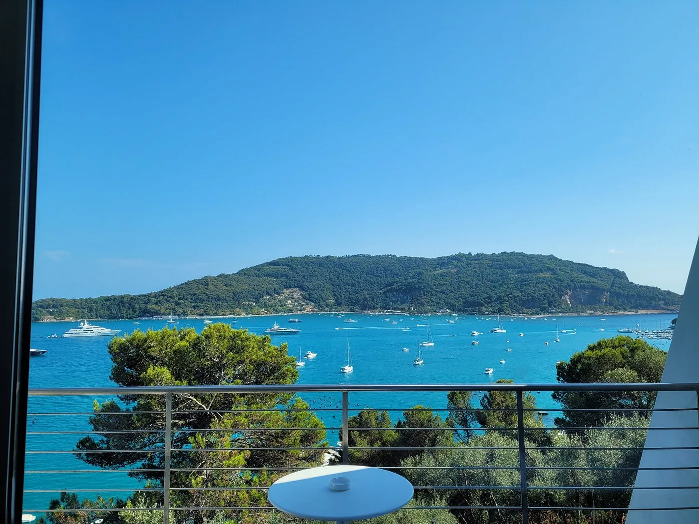 Vista dal balcone sulla baia con barche a vela e isola verde sullo sfondo