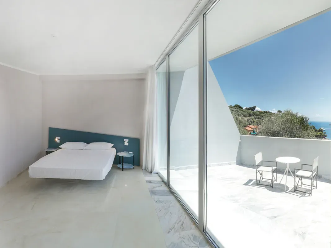 Camera contemporanea con letto sospeso e terrazza privata in marmo con vista mare
