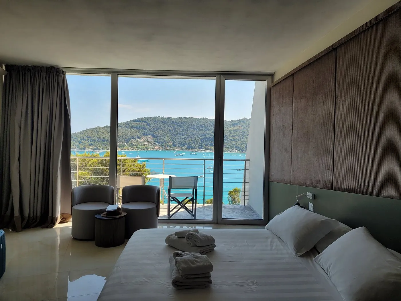 Camera moderna con poltrone, balcone e ampia vetrata affacciata sul golfo