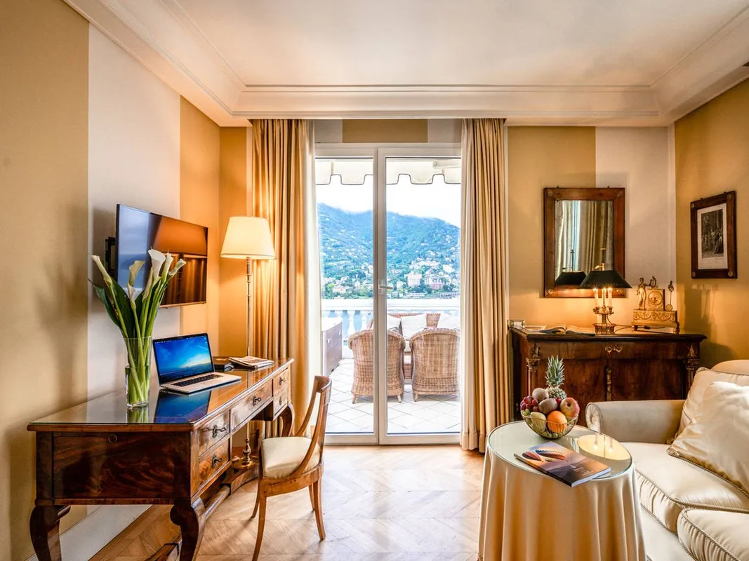 Soggiorno di suite con scrittoio, divano e balcone vista mare e colline