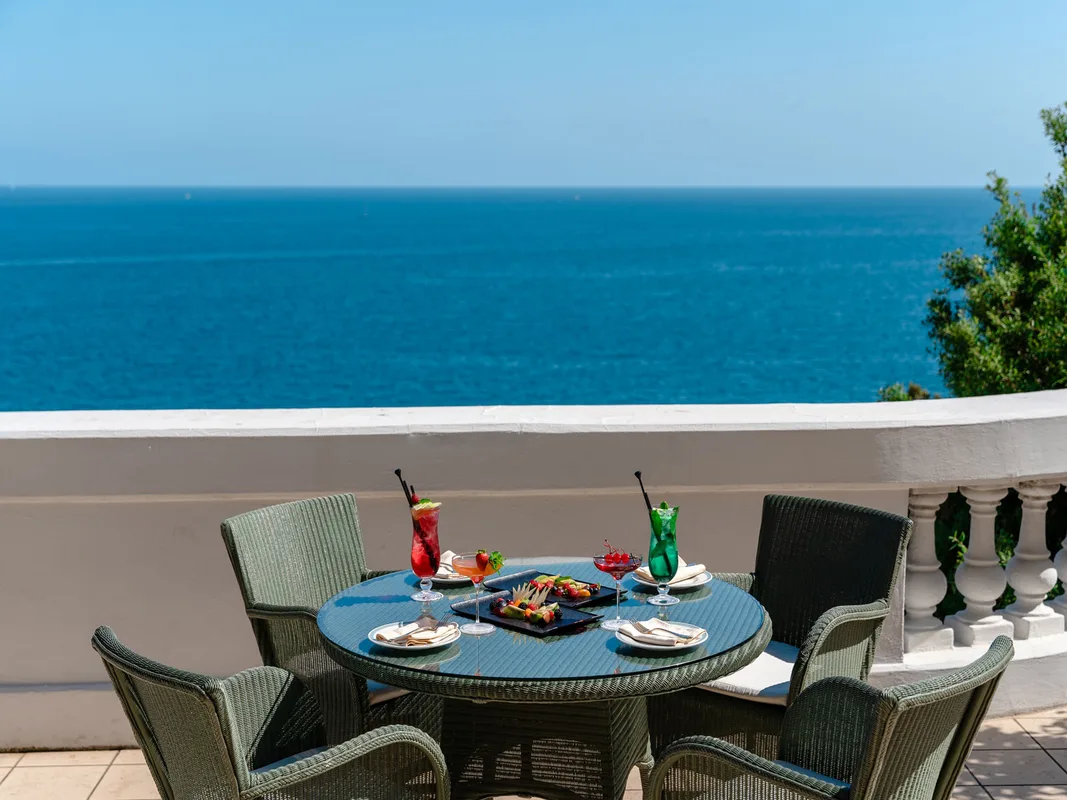 Tavolo su terrazza con cocktail e aperitivo affacciato sul mare blu