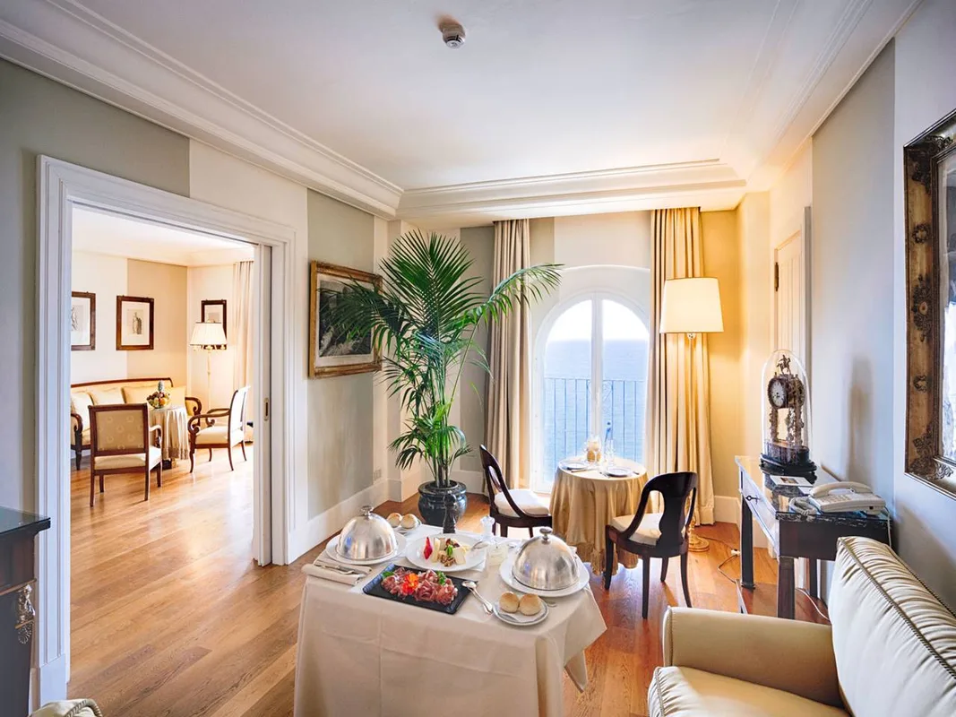 Suite con salotto, room service e finestra ad arco affacciata sul mare