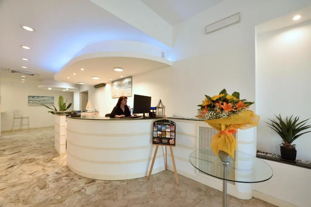 Reception dell'hotel con bancone bianco curvo e composizione floreale