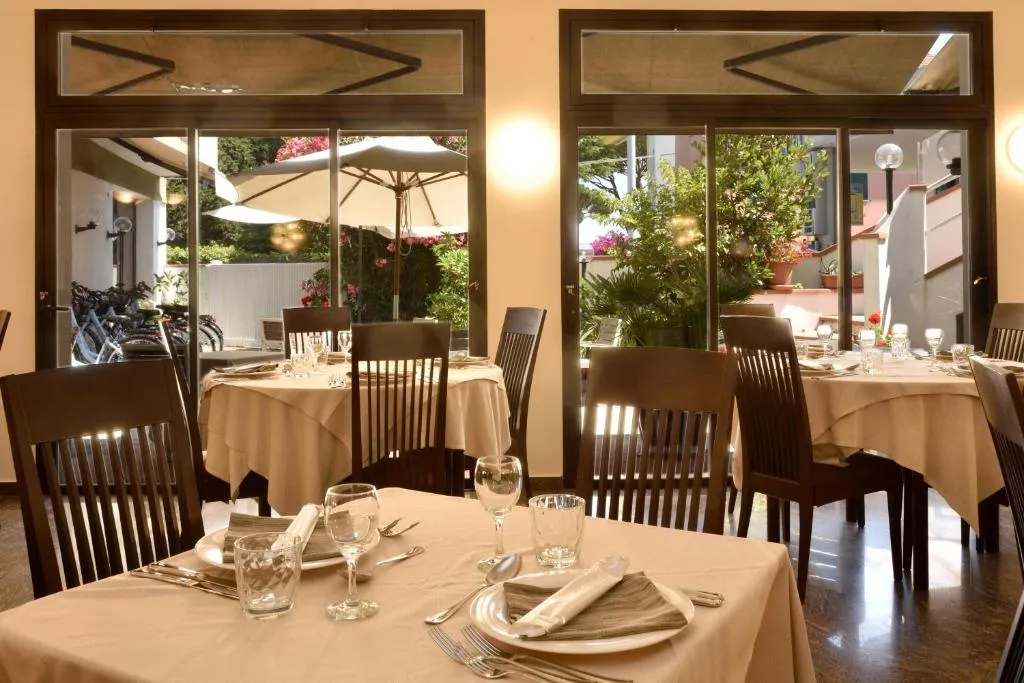 Sala ristorante con tavoli apparecchiati e vista sul giardino esterno