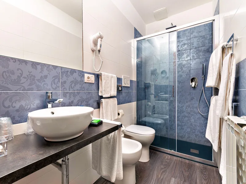 Bagno moderno con doccia a vetro, lavabo a bacinella e piastrelle blu decorate