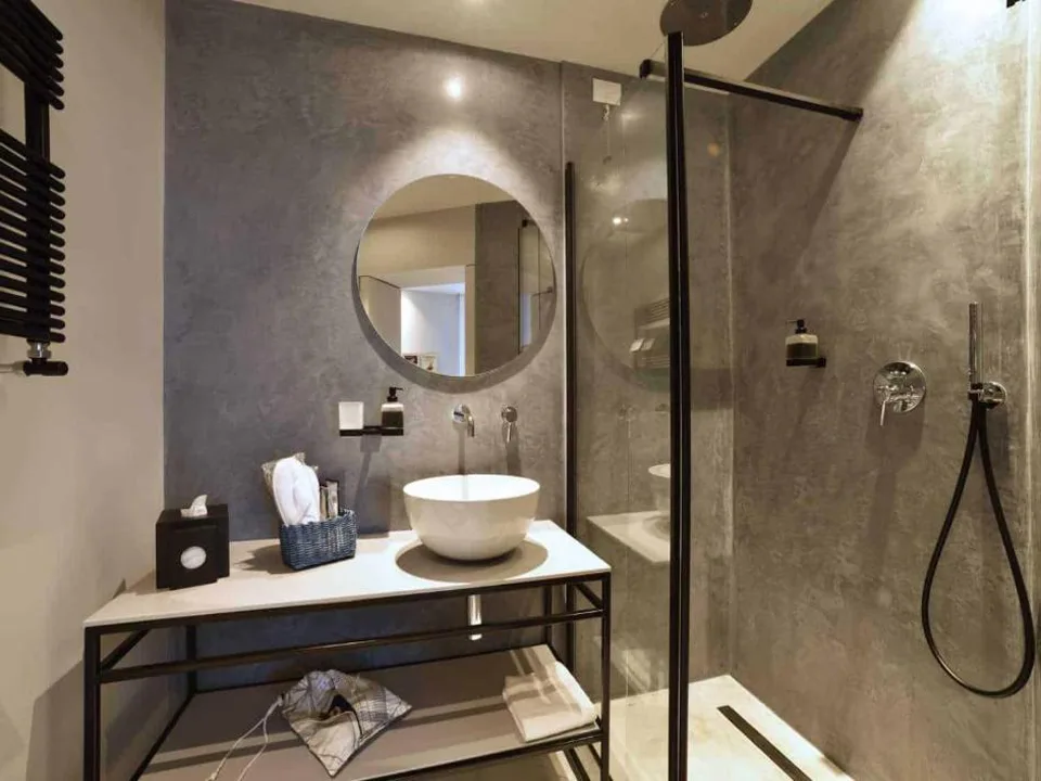 Bagno moderno con doccia in vetro, lavabo a bacinella e specchio rotondo