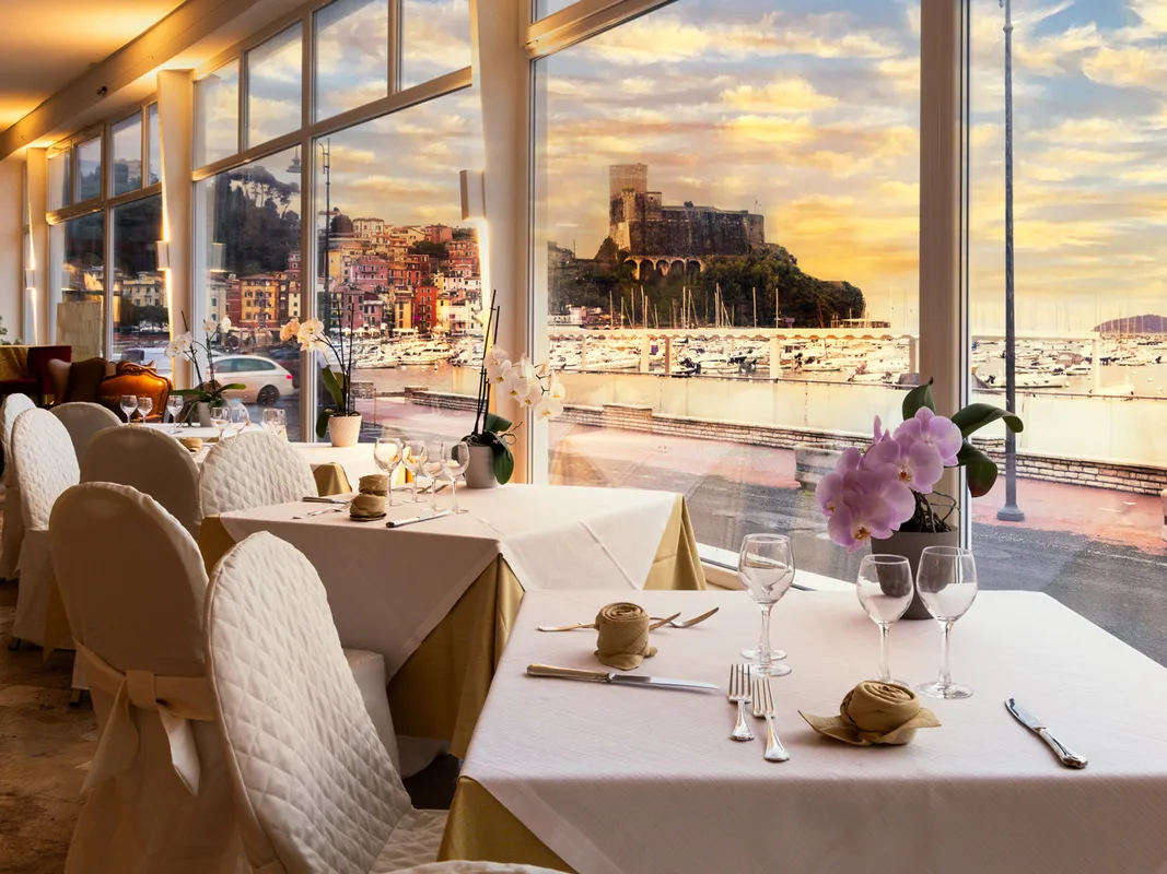 Ristorante con tavoli raffinati e vista sul castello e il porto al tramonto