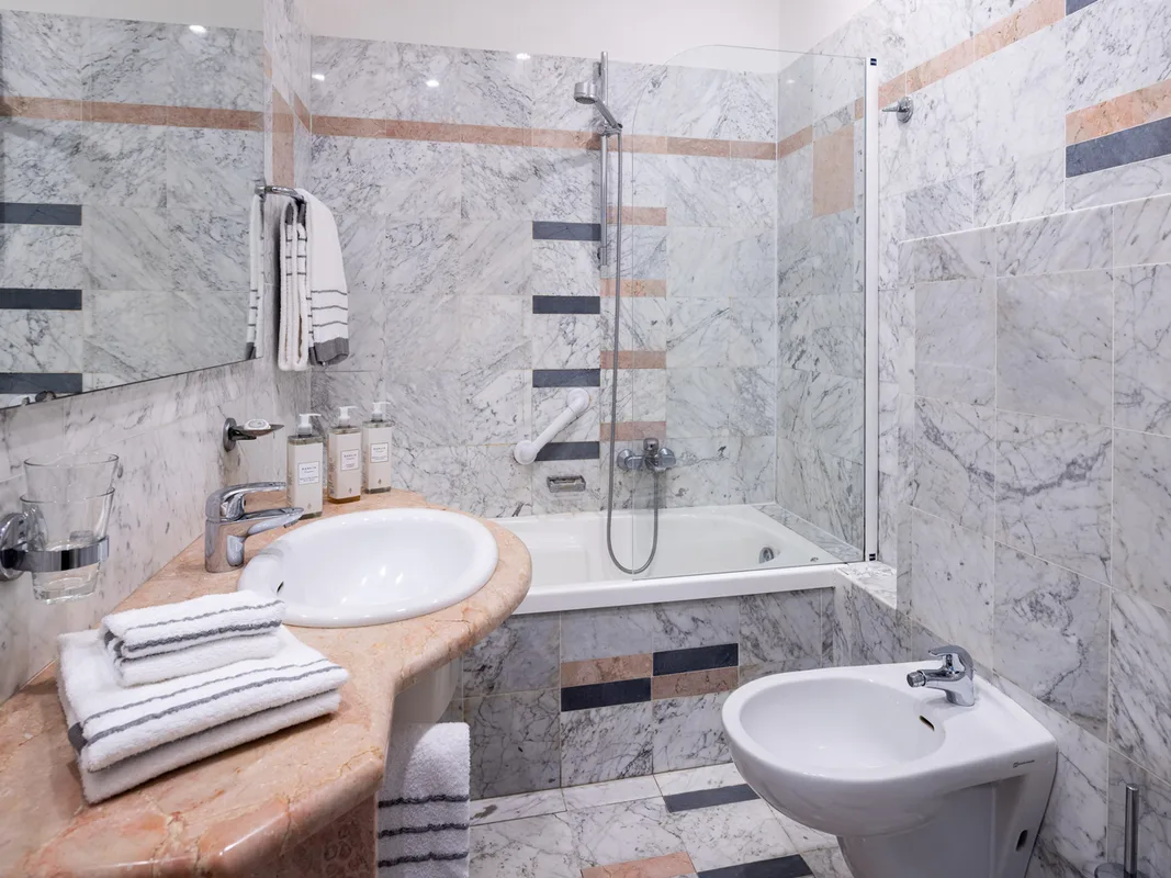 Bagno in marmo con vasca, lavabo, bidet e asciugamani