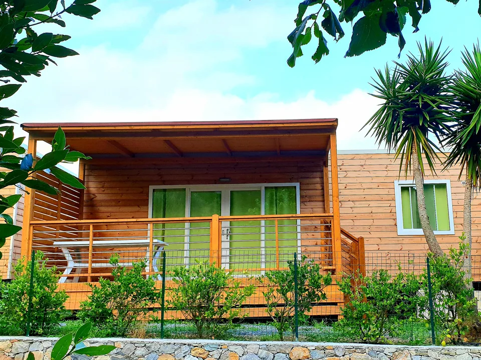 Casa mobile in legno con veranda coperta e palme sullo sfondo