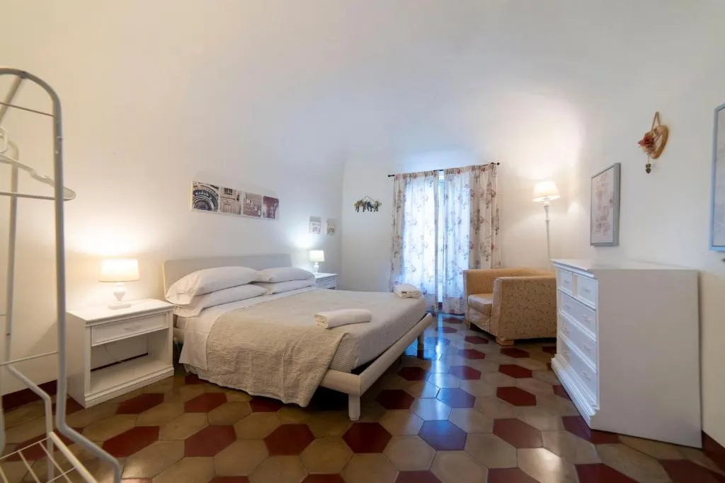 Camera da letto matrimoniale con pavimento esagonale, cassettiera e poltrona