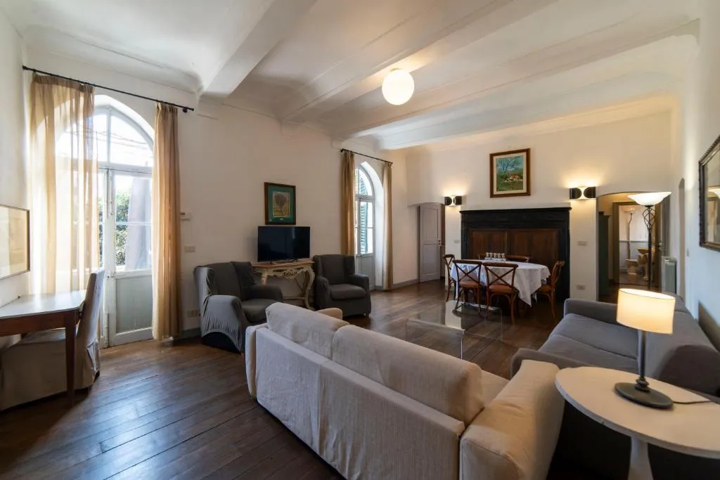 Salotto luminoso con divani, camino in legno e parquet con grandi finestre ad arco