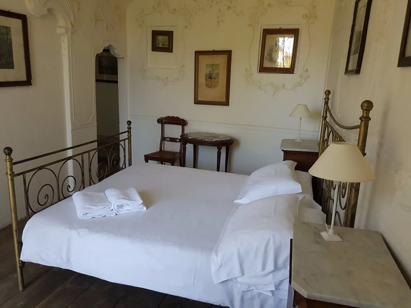Camera da letto d'epoca con stucchi alle pareti, letto in ottone e mobili antichi