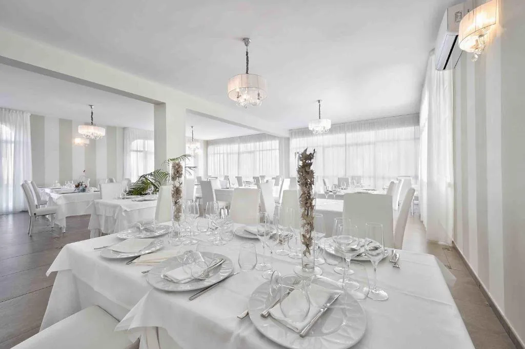 Sala ristorante elegante con tavoli apparecchiati in bianco e lampadari di cristallo