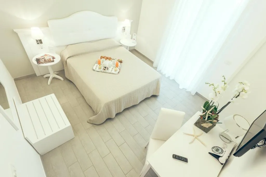 Camera luminosa vista dall'alto con letto matrimoniale, scrivania e arredo bianco
