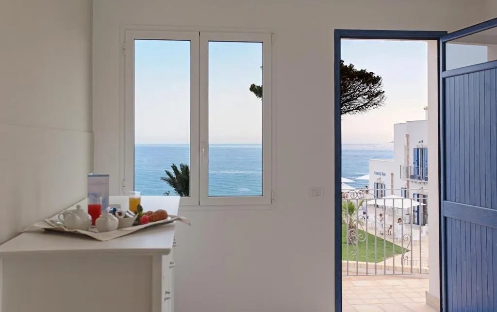 Vista mare dalla camera attraverso finestra e porta-balcone con vassoio della colazione