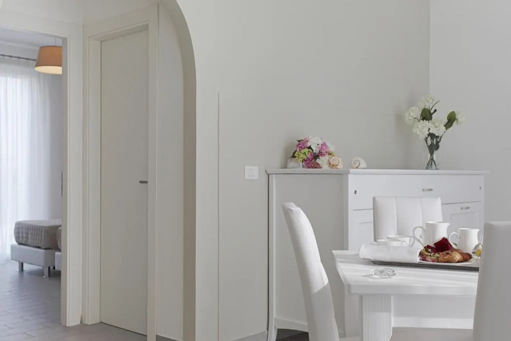 Interno luminoso di appartamento con tavolo bianco apparecchiato per la colazione e arredo bianco