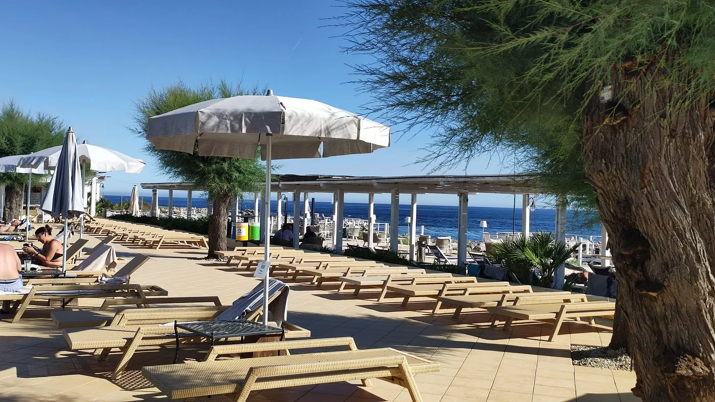 Solarium con lettini in vimini e ombrelloni affacciato sul mare