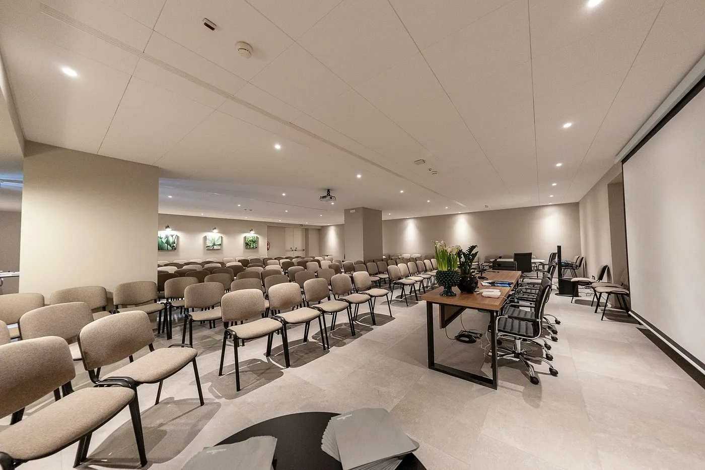 Sala meeting con sedie disposte a platea, tavolo relatori e schermo per proiezioni