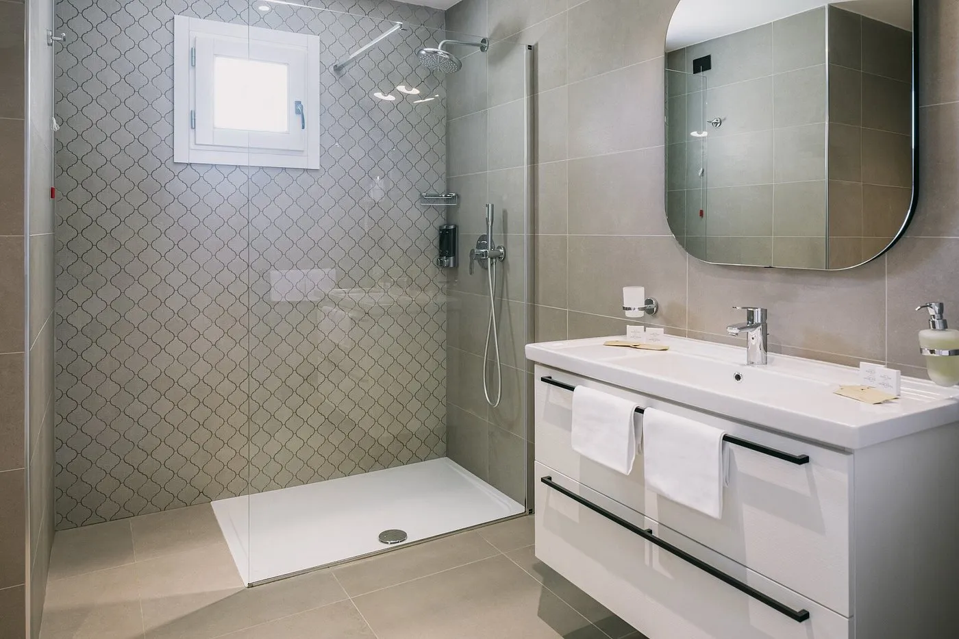 Bagno moderno con doccia in vetro, lavabo bianco e specchio