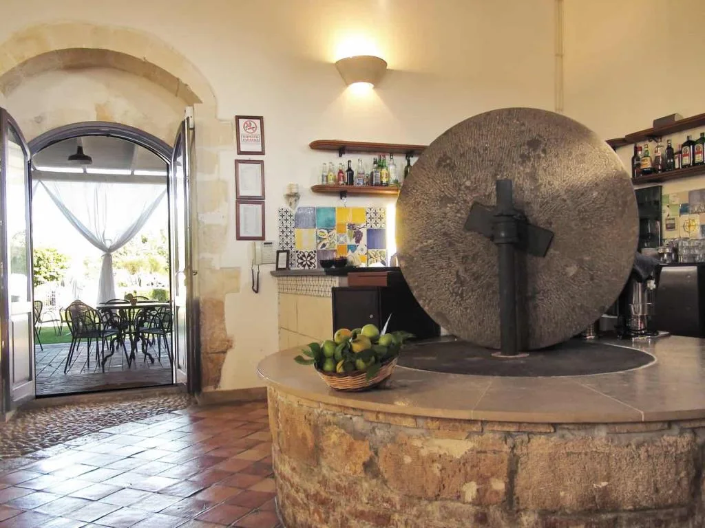 Bar interno con antica macina in pietra, basket di limoni e affaccio sulla terrazza esterna